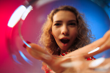 Image showing The surprised young woman in party clothes posing with glass of wine.