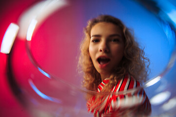 Image showing The surprised young woman in party clothes posing with glass of wine.