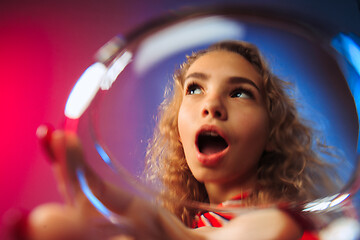 Image showing The surprised young woman in party clothes posing with glass of wine.