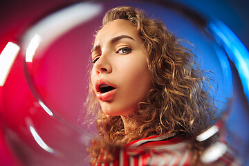 Image showing The surprised young woman in party clothes posing with glass of wine.