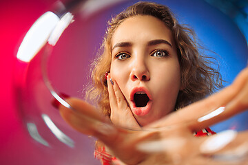 Image showing The surprised young woman in party clothes posing with glass of wine.