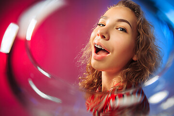 Image showing The surprised young woman in party clothes posing with glass of wine.