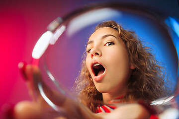 Image showing The surprised young woman in party clothes posing with glass of wine.