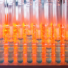 Image showing Glass test tubes containing blue liquid on warm orange background.