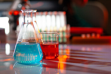 Image showing Illuminated laboratory flask filed with colorful chemical solutions with shadows on the table. Laboratory, science, chemistry... consept.