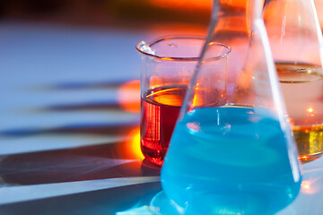 Image showing Illuminated laboratory flask filed with colorful chemical solutions with shadows on the table. Laboratory, science, chemistry... consept.