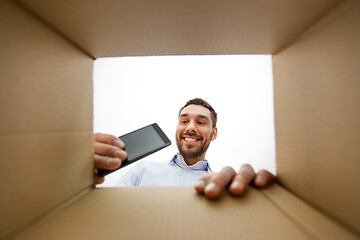 Image showing smiling man taking smartphone out parcel box