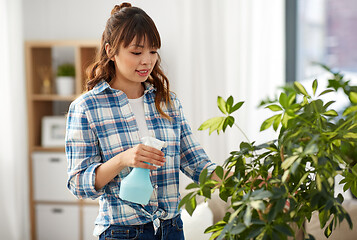 Image showing happy asian woman spraying houseplant at home