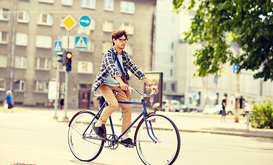 Image showing young hipster man with bag riding fixed gear bike