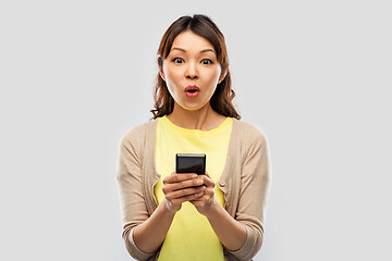 Image showing surprised asian woman using smartphone