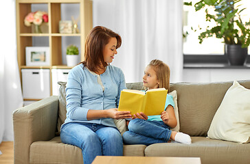 Image showing happy girl with mother reading book at home