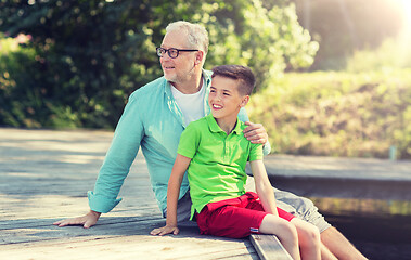 Image showing grandfather and grandson sitting on river berth