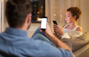 Image showing couple with smartphones at home in evening