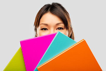 Image showing asian woman or student hiding behind notebooks