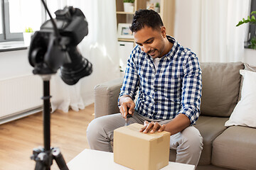 Image showing male video blogger opening parcel box at home