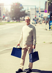 Image showing senior man with shopping bags walking in city