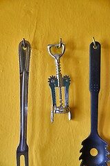 Image showing Corkscrew and othe utensils on a kitchen wall