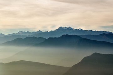 Image showing Mountain peaks above moving clouds and mist