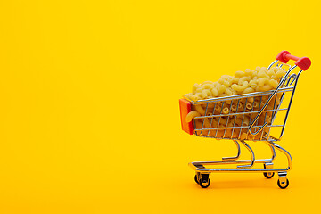 Image showing Grocery trolley filled with pasta on a bright orange background