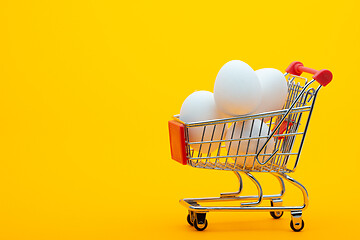 Image showing White chicken eggs are in the grocery cart, bright orange background