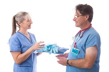 Image showing Hospital healthcare worker hands a PPE kit to another nurse or d