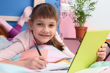 Image showing Happy schoolgirl studies remotely at home, lies in bed and joyfully looked into the frame