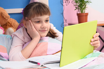 Image showing The girl lies in bed and looks at the tablet video tutorials