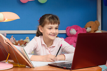 Image showing Smiling girl at table at home studying at school.