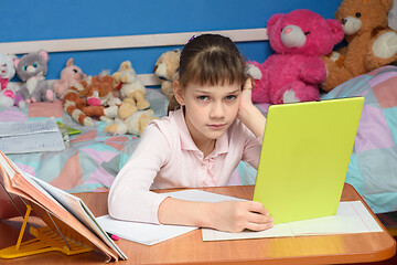 Image showing The girl was forced to do homework and watch a boring video tutorial on a tablet