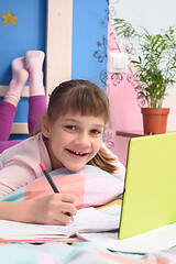 Image showing Happy schoolgirl studying at home lying in bed