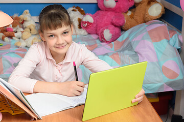 Image showing The girl is studying remotely at home and looked into the frame