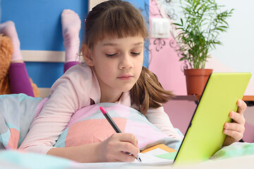 Image showing Student in her bed at home studying at school online