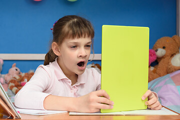 Image showing Girl at home at the table yawns while watching a boring video tutorial