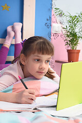 Image showing Schoolgirl watches video tutorials in a tablet computer and lies in bed