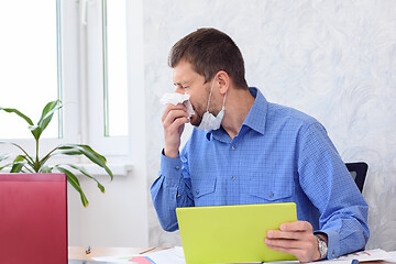 Image showing A sick employee sneezes in an office and works remotely