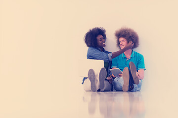 Image showing multiethnic couple sitting on the floor with a laptop and tablet