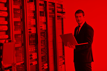 Image showing businessman with laptop in network server room