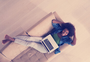 Image showing African American woman using laptop on sofa top view