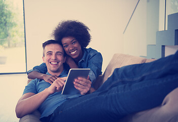 Image showing multiethnic couple relaxing at  home with tablet computers