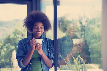 Image showing African American woman drinking coffee looking out the window