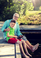 Image showing grandfather and boy with tablet pc on river berth