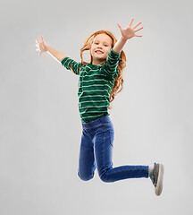 Image showing smiling red haired girl in striped shirt jumping