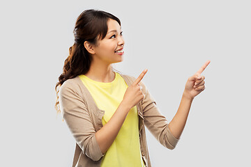 Image showing happy asian woman pointing fingers up