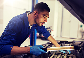 Image showing mechanic man with lamp repairing car at workshop