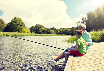 Image showing grandfather and grandson fishing on river berth