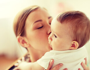 Image showing happy young mother kissing little baby at home