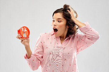 Image showing shocked young woman in pajama with alarm clock