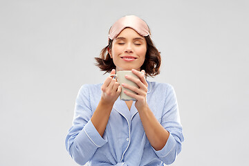 Image showing woman in pajama and sleeping mask drinking coffee