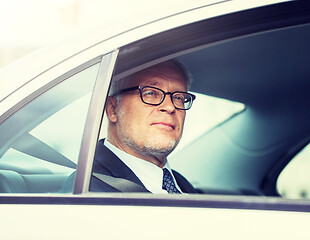 Image showing senior businessman driving on car back seat