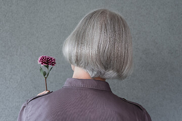 Image showing Elegant gray-haired woman holding red flower